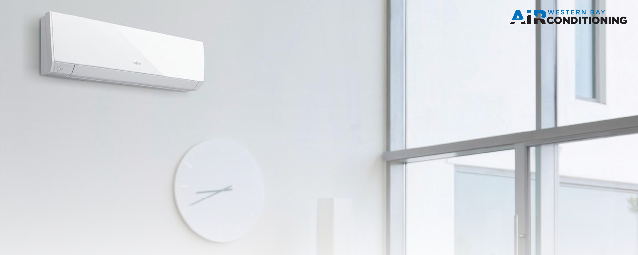 A white wall-mounted air conditioner that includes a clock on its surface.